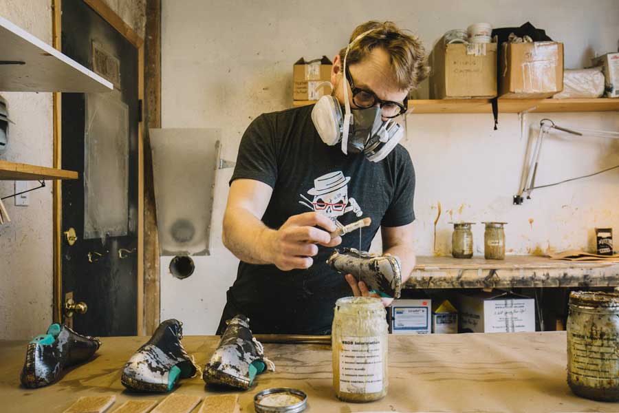 Man coloring a shoe in warehouse