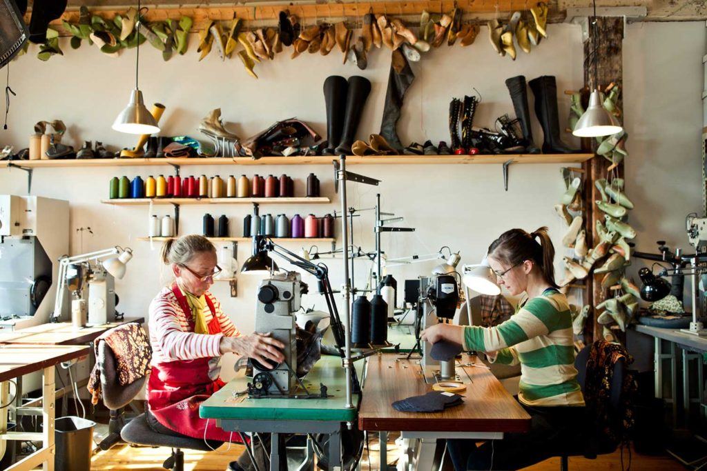 2 women stitching shoe in warehouse