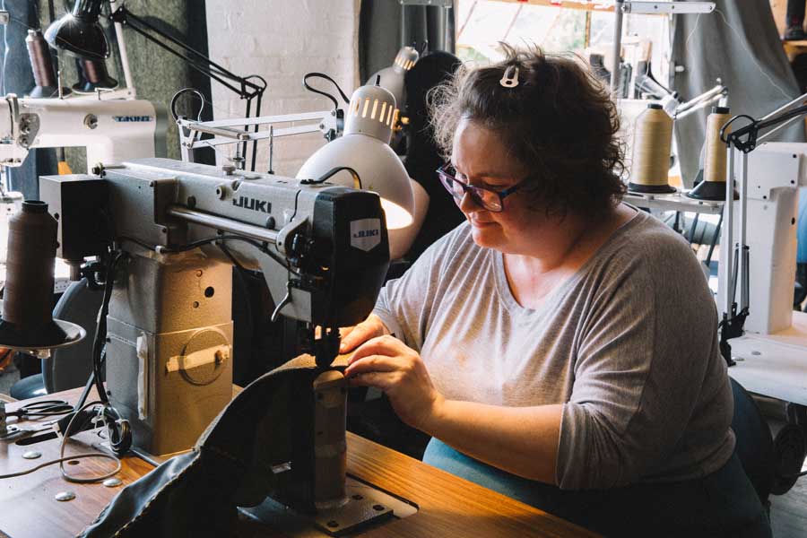 a shoemaker sewing leather on a sewing machine