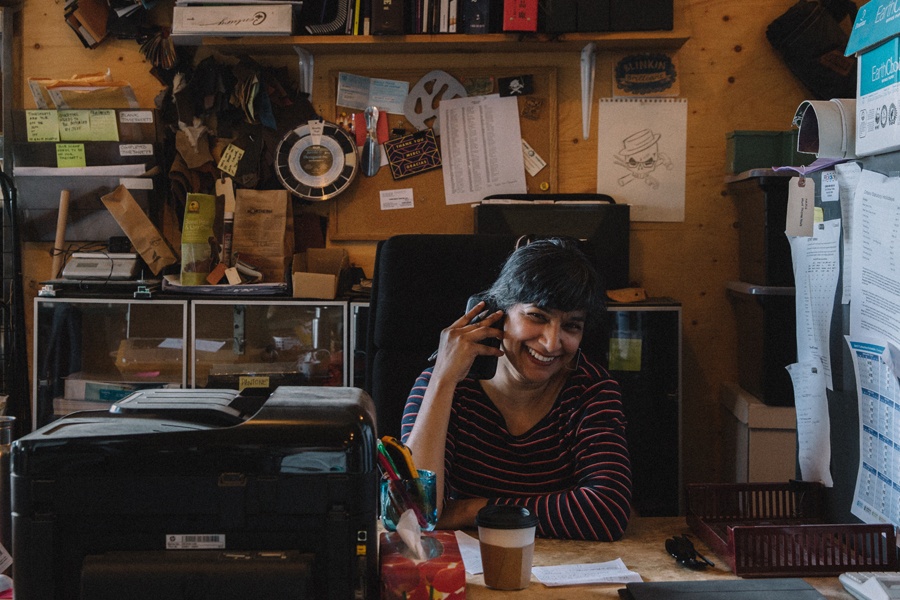 a person sitting behind an office desk and smiling while talking on a cell phone