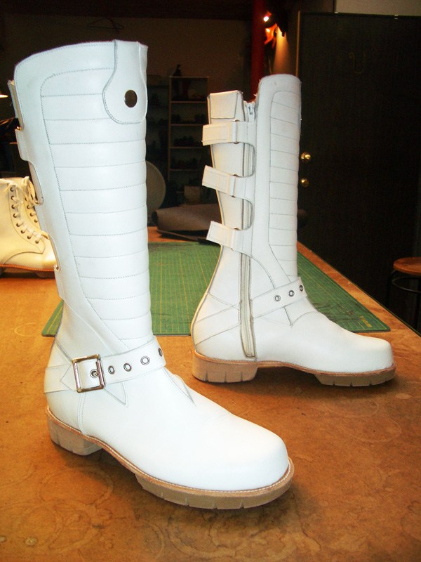 pair of white long boots with buckle and zip
