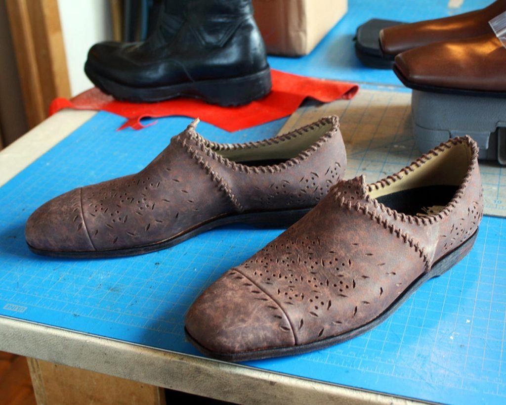 a pair of brown shoes with stitching design
