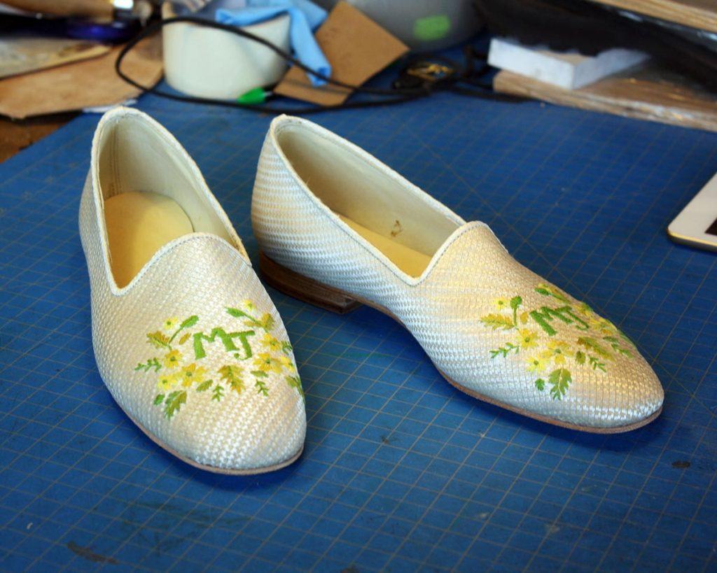 a pair of white shoes with green embroidery