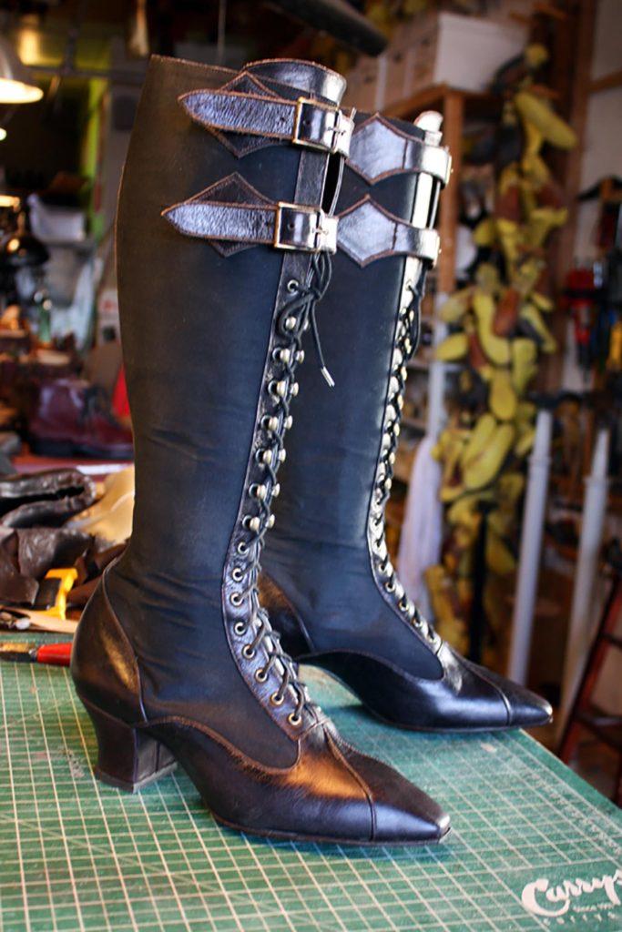pair of black long boots with buckle and lace