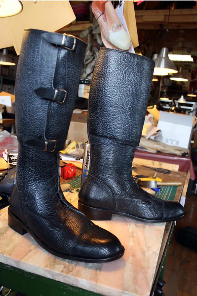 pair of black long boots with buckle