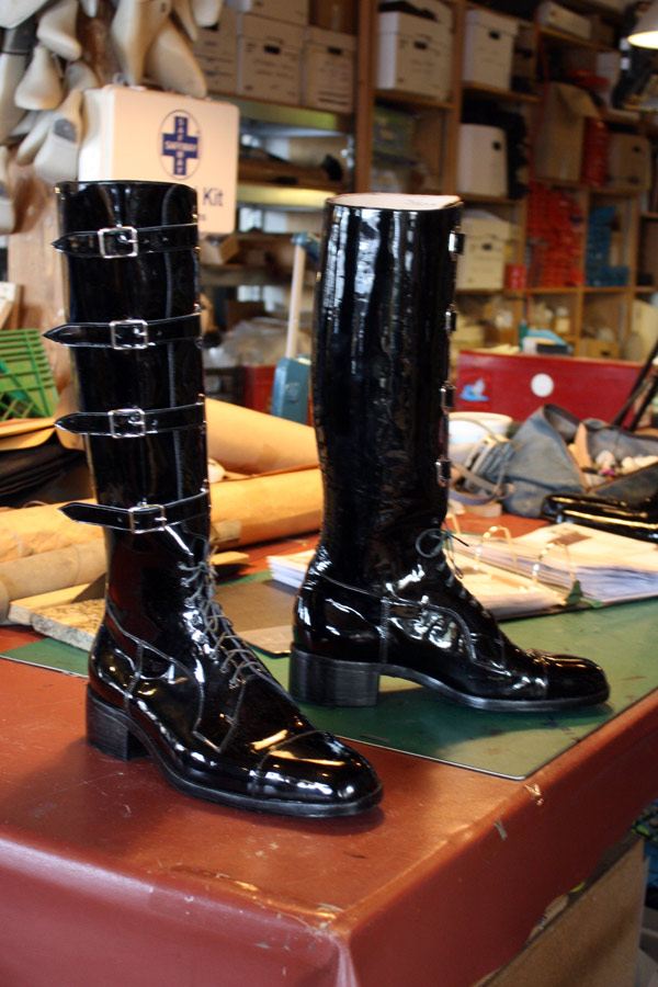 shiny black knee length boots with four straps and buckles